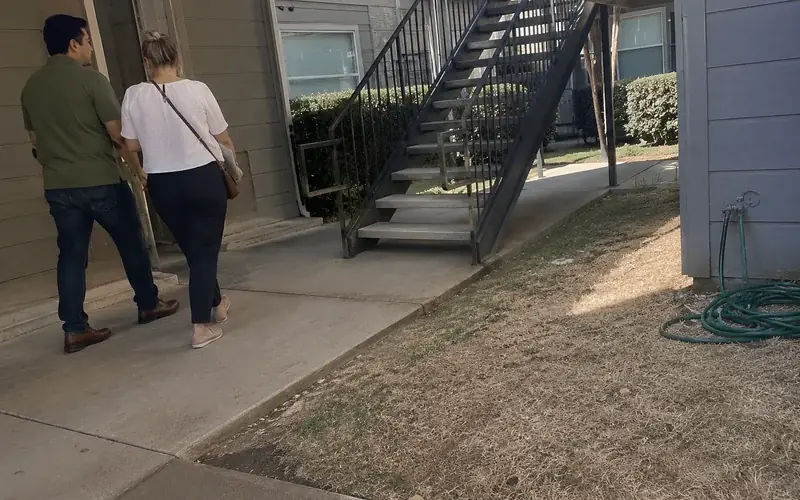 Apartment breezeway with painted metal handrails and exterior stairs in overcast light