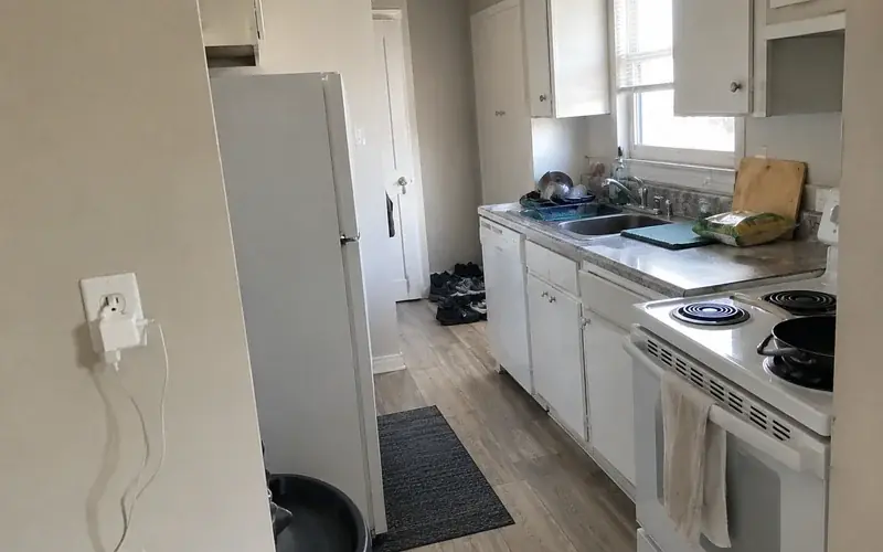 Apartment galley kitchen with laminate counters, white appliances, and vinyl plank flooring
