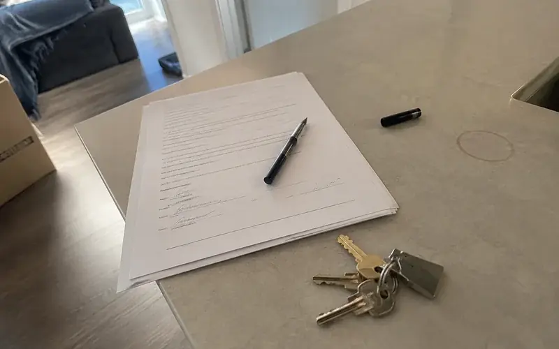 Apartment keys and a signed lease packet on a laminate countertop