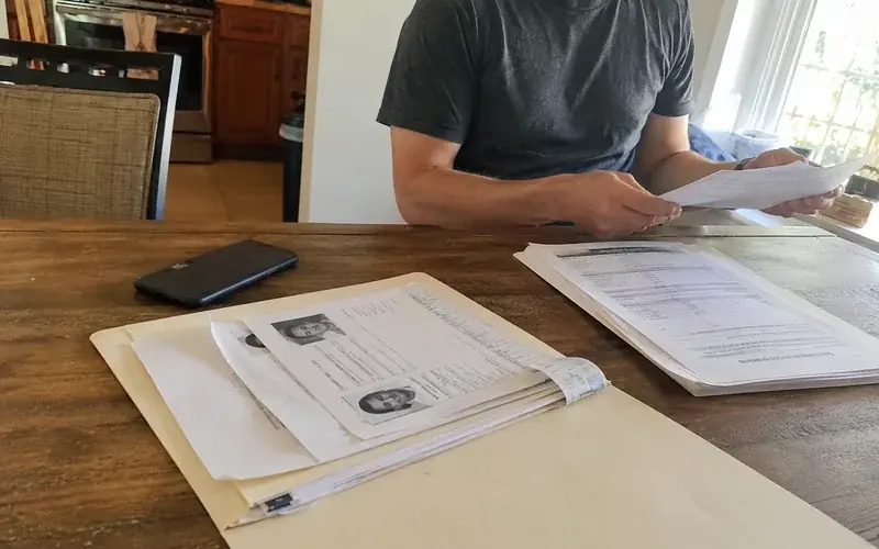 Document folder with ID, pay stubs, and court paperwork laid out on a kitchen table
