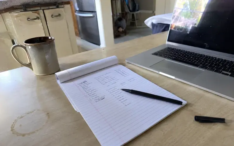 Notepad listing case categories and disposition dates beside a laptop and a coffee cup