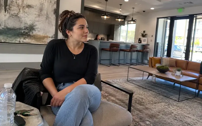 Person seated waiting in an apartment leasing lobby, casual clothing, unposed