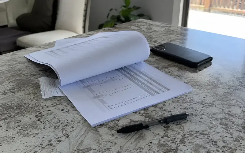 Printed rental history report pages beside a phone and a pen on a kitchen table