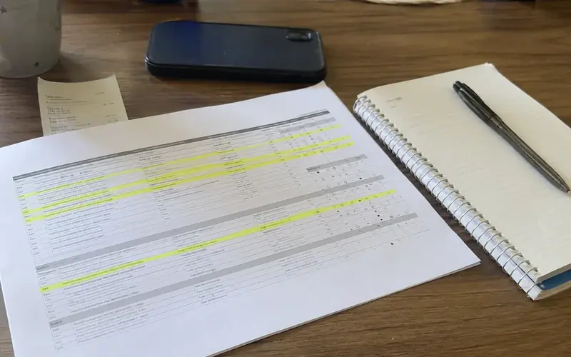 Printed screening report summary page with highlighted lines beside a notepad and pen