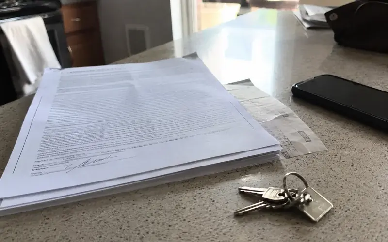 Signed lease packet and a set of apartment keys on a laminate countertop