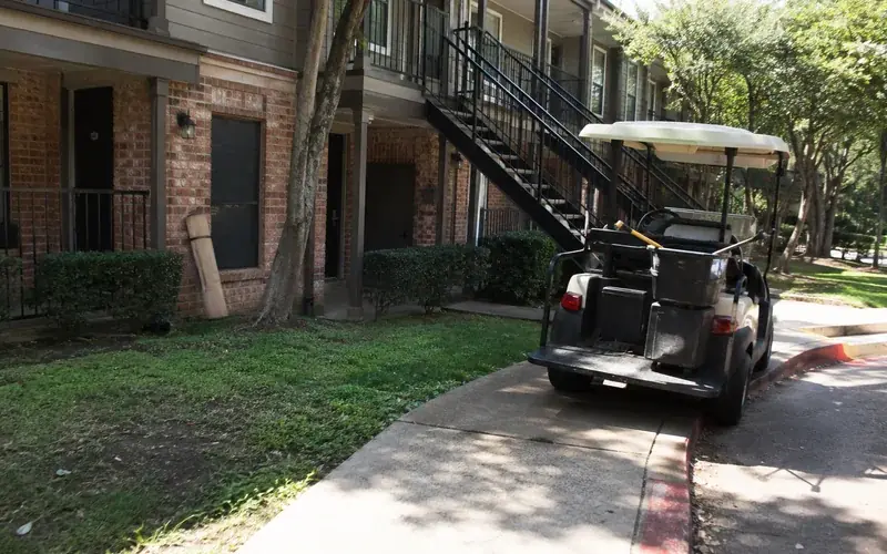 Three-story garden-style apartment exterior with red brick and breezeway stairs