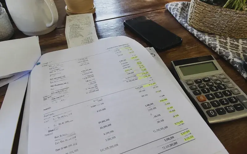 Twelve-month earnings summary printout with highlighted totals beside a calculator