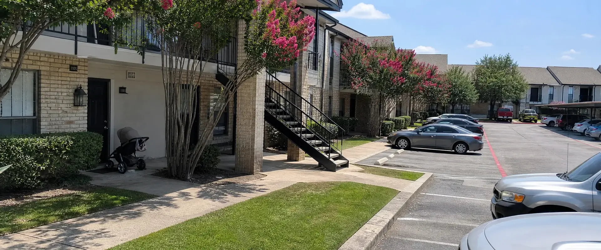 Fort Worth apartment breezeway stairs with painted metal handrails against a red brick wall
