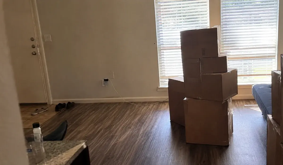 Cardboard moving boxes stacked in an empty apartment with vinyl plank floors