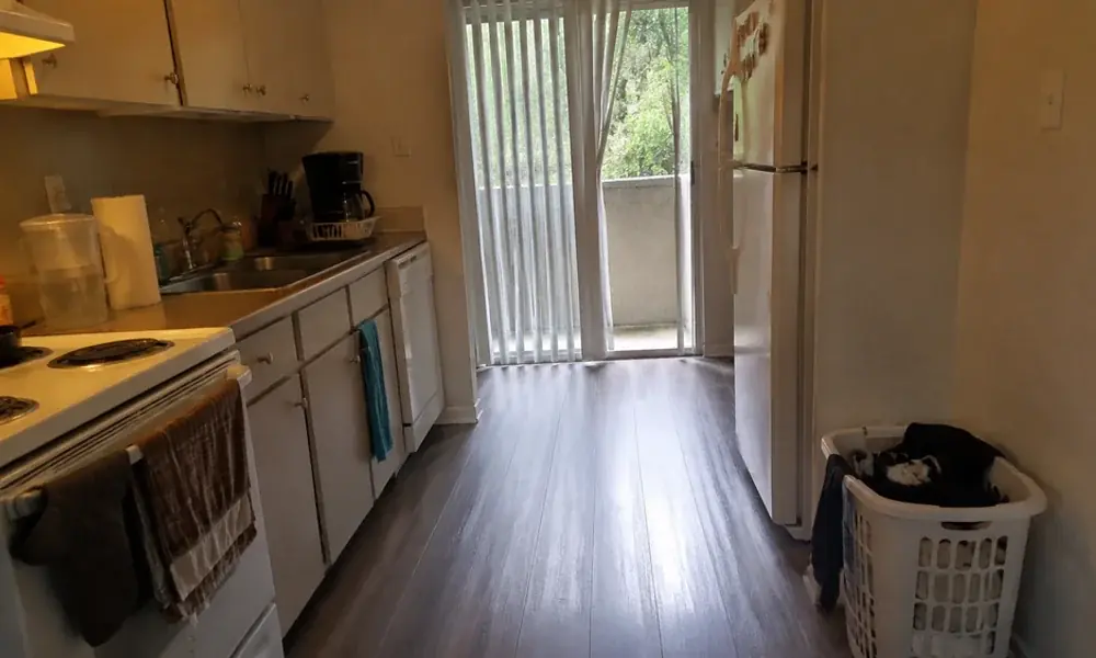 Galley apartment kitchen with laminate counters and white appliances