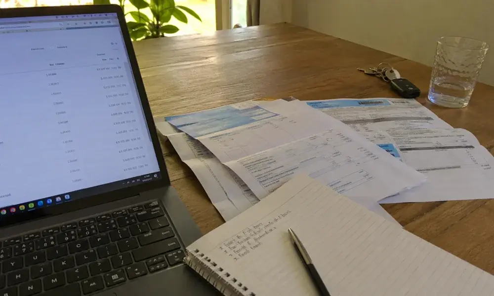 Laptop showing bank transaction history and utility bills used for alternative credit scoring in Fort Worth