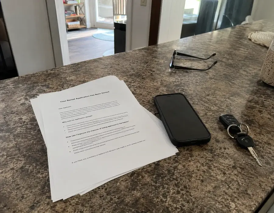 Rental application denial letter and a phone left on a kitchen counter