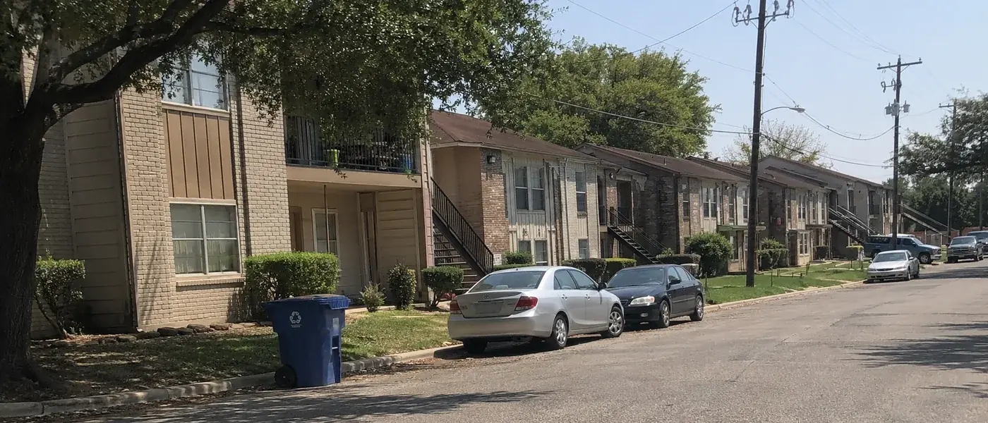 Row of apartment buildings on a residential street with parked cars out front